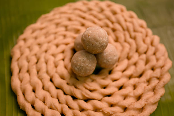 Three round sweets sit on a woven plate made from dough, showing local cuisine during a celebration.
