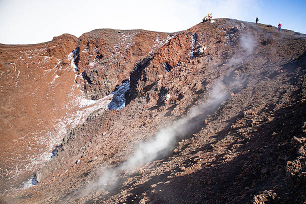 View of Mount Etna in Sicily with a guided tour group hiking along volcanic trails. Tourists explore the iconic volcano, enjoying scenic landscapes and volcanic features during an organized trekking adventure.