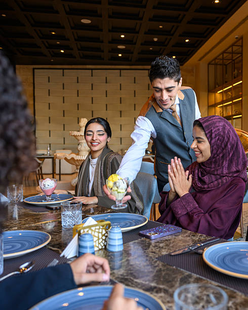 Waiter serving ice cream to friends in restaurant