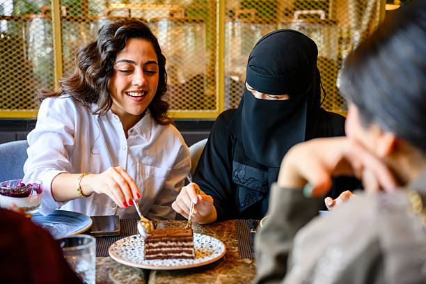 Diverse young women enjoying cake and coffee in cafe