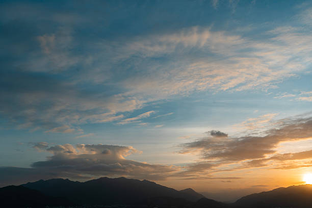 Bright sunset over the silhouette mountains at evening time.