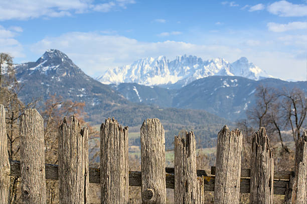 Old wooden fence on a mountain plot with a view of the Alps in the background