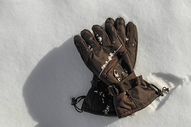 Overhead view of winter gloves resting on fresh snow.