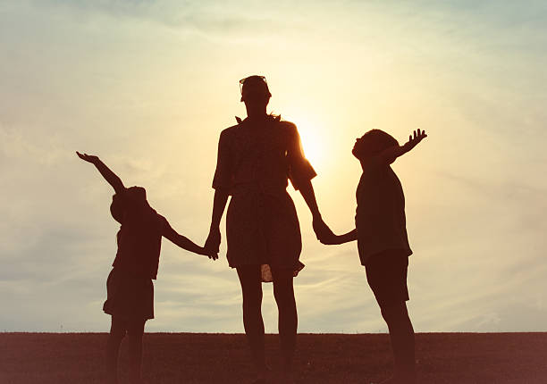 Mother and her children holding hands at sunset.