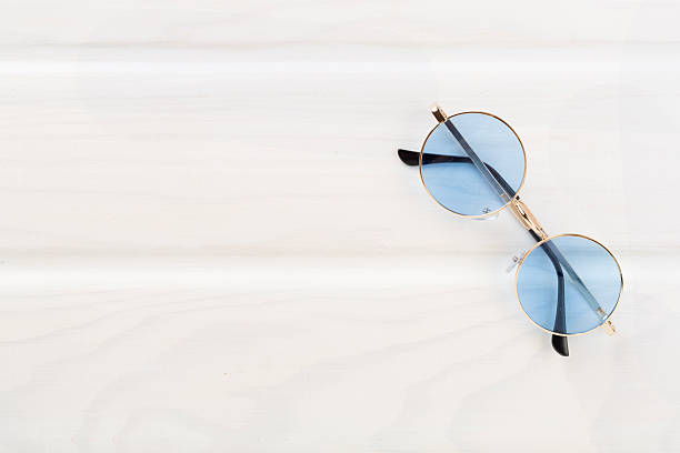 Blue sunglasses on wooden background, top view
