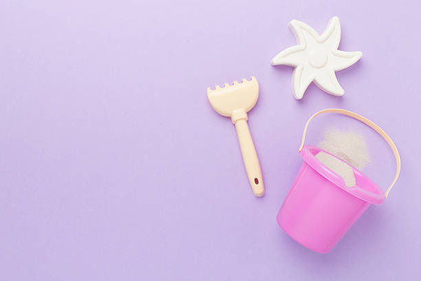 Cute toys for playing with sand on color background, top view
