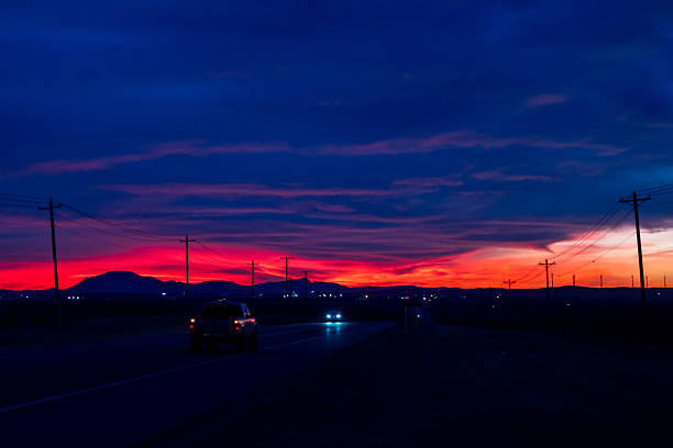 Dramatic sunset sky over country road with passing vehicles