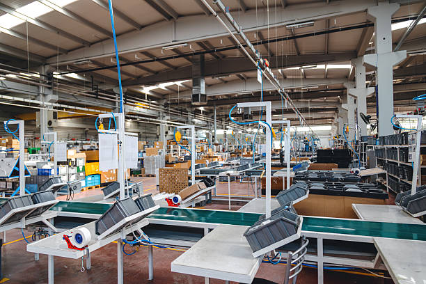 Wide angle view of empty manufacturing facility featuring conveyor systems, packaging equipment and assembly workstations under bright industrial lighting, clean organized production environment representing automation, logistics and mass production industry with copy space