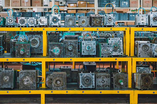 Front view of heavy steel mold tooling units arranged in numbered shelves within industrial workshop environment, showing organized production workflow, maintenance storage system, engineering equipment and mass manufacturing process in factory interior