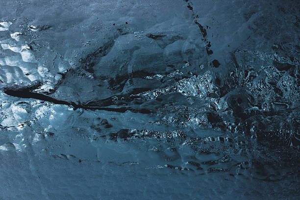 Deep blue ice forms an abstract organic texture with natural patterns and cool tones, highlighting the cold, crystalline beauty of a frozen glacier landscape