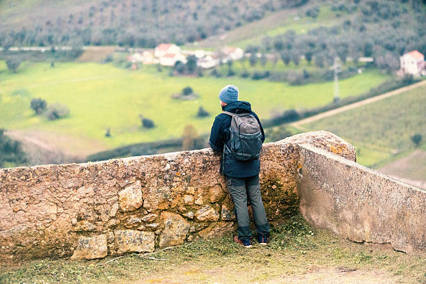 Backpack with a scallop shell attached is leaning against a stone wall in santiago de compostela, spain