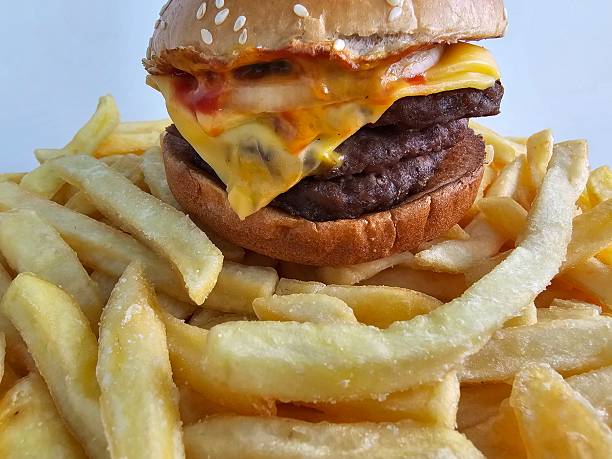 Juicy hamburger with two beef patties and cheese served with a large portion of French fries in a fast food