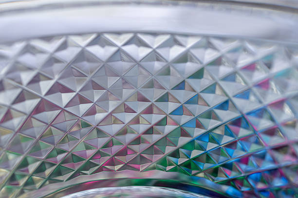 This image shows a defocused macro abstract texture background view of a beautiful vintage lead crystal glass bowl surface with diamond facet cuts, reflecting colors.