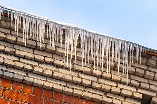 Close-up of shiny icicles on a roof gutter on a sunny day.
