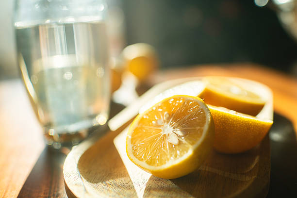 Lemons and a glass of water in sunny morning