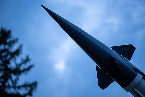 Side shot of a military Tomahawk missiles flying in formation over forest area with the ground blurred and some mountains visible in the background