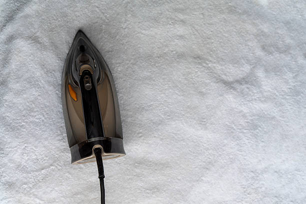 Top view of modern steam iron on white towel background