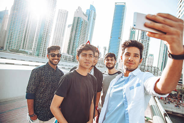 A group of young men gather closely while taking a selfie outdoors, capturing friendship, travel memories, and modern social behavior in an urban setting.