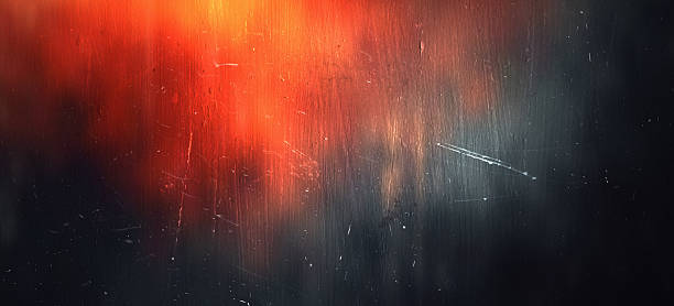 Closeup of abstract red and blue light leak glow over a dark scratched surface, creating a moody grunge texture background with copy space.