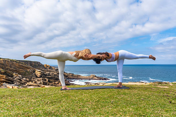 istock Two women practicing partner yoga on cliff overlooking ocean 2261222742