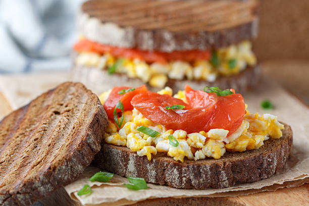 Scrambled eggs and smoked salmon on rye bread with green onions. A sandwich for breakfast. Selective focus