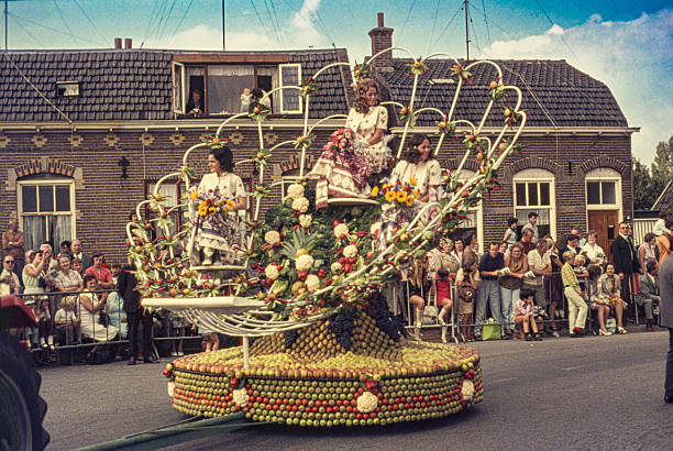 Historical slide showing a decorated float during the Harvest and Fruit Parade (Oogst- en Fruitcorso) in Tiel in the 1960s. The float, adorned with fruit, vegetables and natural materials, passes spectators lining the street. The annual parade in the Betuwe region is known for its elaborate fruit decorations and festive procession. September 1968, Tiel, Gelderland, The Netherlands.