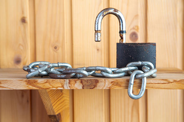 Man's Hand Holding Padlock on Door; Locking or Unlocking