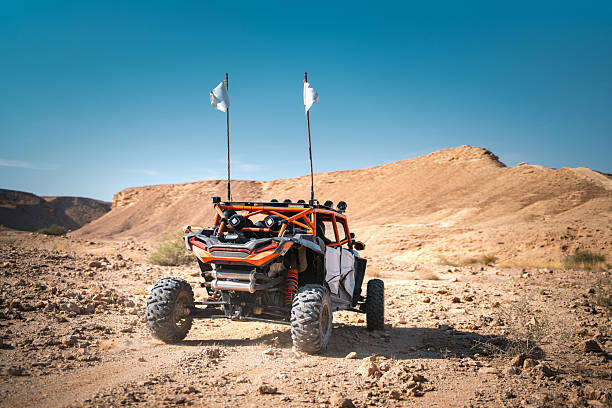 Arab tourists driving a buggy through rugged desert terrain in Saudi Arabia. Clear skies enhance the scenic desert backdrop, highlighting the adventure and thrill of off-road exploration in a vibrant landscape.