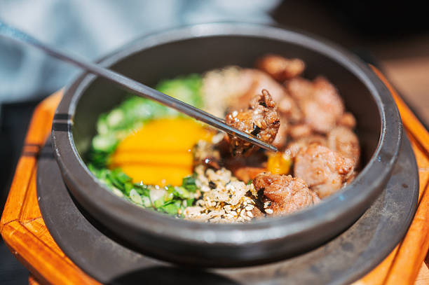 close-up korean bibimbap style beef rice in heated stone bowl highlighting sizzling texture, contemporary asian cuisine and premium casual dining concept
