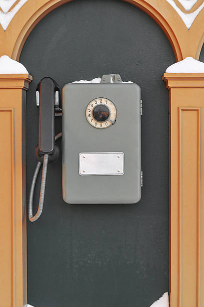 Close up of black obsolete rotary payphone on red wood background.