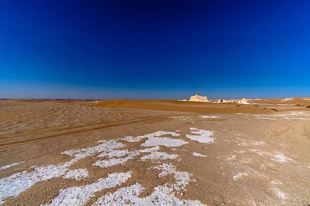 White salt crust patterns spreading across sandy ground in Egypt's White Desert near Farafra, highlighting texture, contrast, and extreme arid conditions.