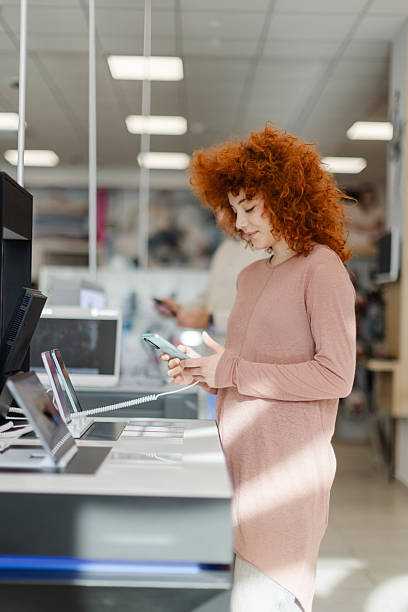 istock Shopping for the latest technology in an electronics store during the day with a customer examining a smartphone 2261263188