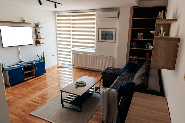 Spacious living room interior featuring a sofa, wooden coffee table, TV unit, and parquet flooring.