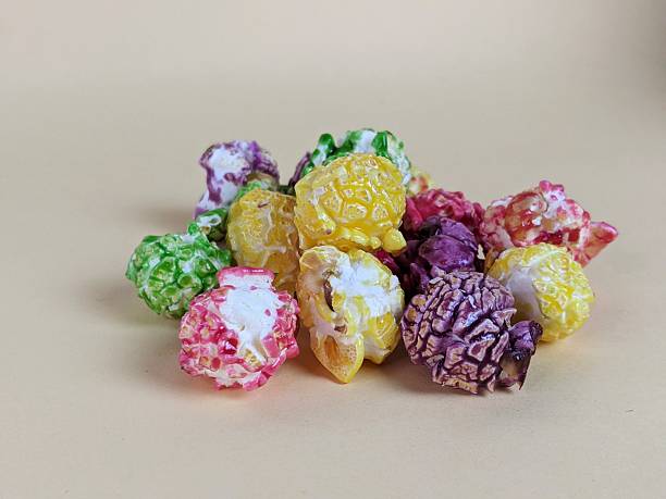 Pile of brightly glazed colorful popcorn kernels on beige surface.