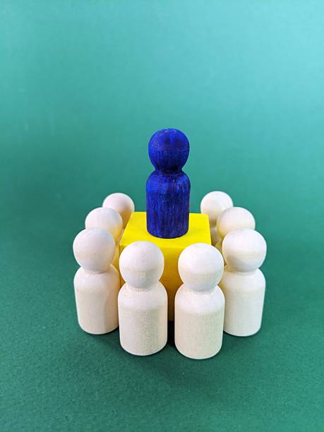 Wooden figurines encircle central leader on cube, symbolizing leadership, teamwork and organizational guidance