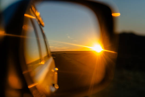 Golden sunset reflected in a car side mirror while driving through Egypt's desert landscape, conveying travel, journey, freedom, and motion at dusk.