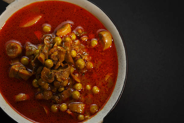 Traditional mushroom matar curry served in a bowl, photographed from top angle showcasing vibrant red gravy and ingredients.