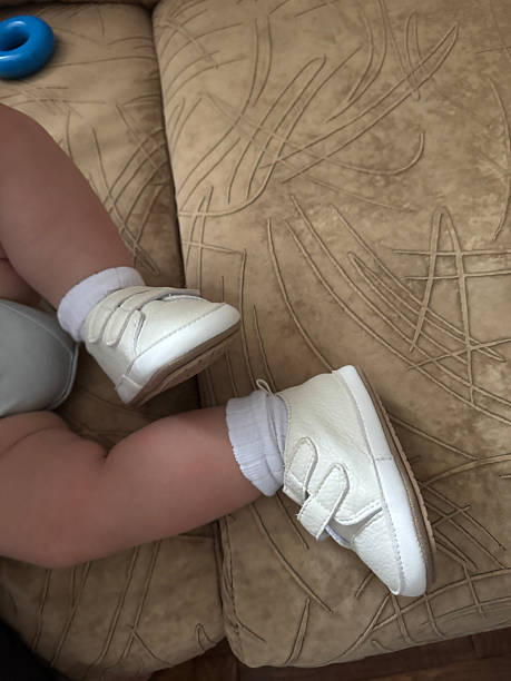 Baby Legs Wearing White Shoes While Sitting Indoors