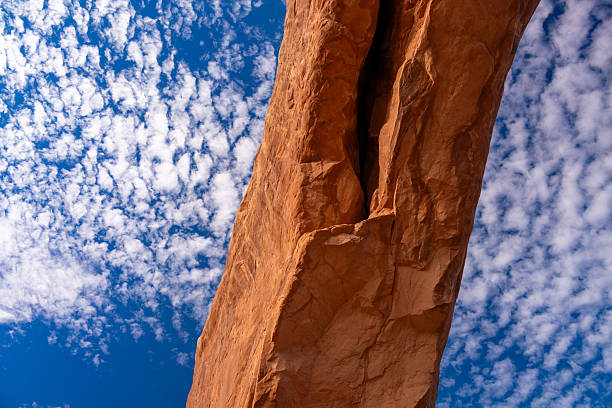 Red Sandstone Rock Arch Formation - Scenic landscape in desert canyon area with large rock arches against crisp blue sky. Scenic desert landscape with late afternoon warm light.