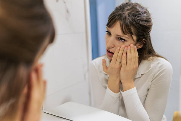 istock Woman Examining Face In Bathroom Mirror 2261272761