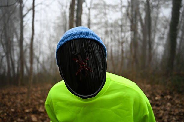 Person wearing a neon mask and bright shirt standing in a foggy winter forest
