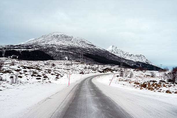 Snowy road stretching towards distant mountains under a winter sky