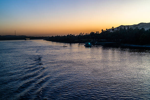 Pyramids of Giza, Giza Necropolis, Egypt - July 26, 2022: Two men rowing a small boat during sunset on the Nile River.
