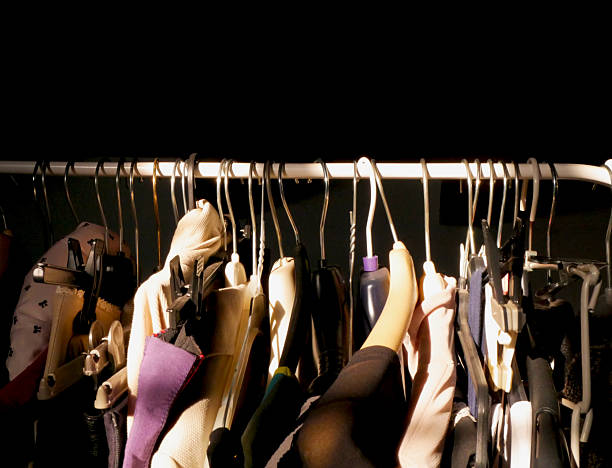 close up of some clothes and hangers on a clothing rack with a dark background