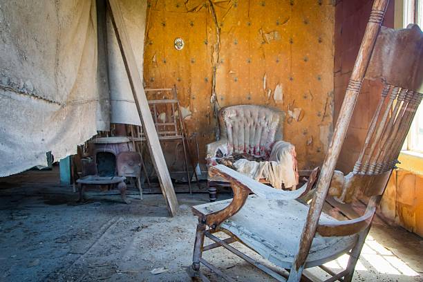 Interior of a weathered wooden cabin with rocking chair and stove, reflecting frontier heritage and rural western history with natural interior copy space.