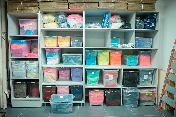 Storing colorful textile materials in clear plastic bins on white shelving in a workshop