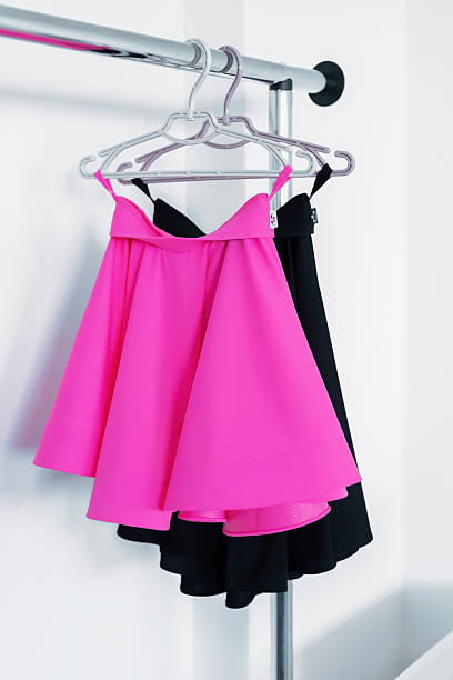 Bright pink skirt and black skirt hanging on a metal clothing rack