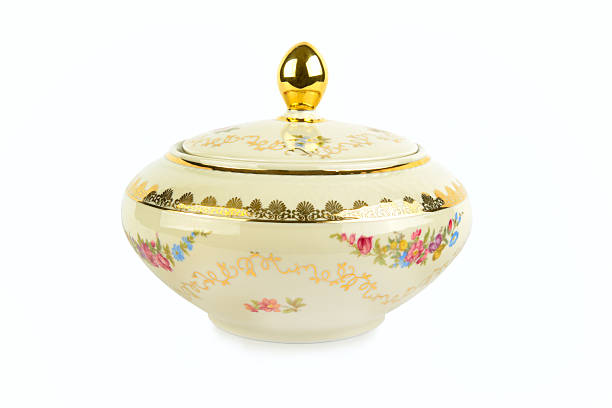 An elegant vintage porcelain candy bowl with intricate floral patterns and gold accents is isolated on white. This classic tableware piece is perfect for antique collections or tea party themes.
