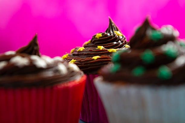 Close up shot of unrecognizable woman holding a cute Halloween themed cupcake in the palm of her hand against a window.