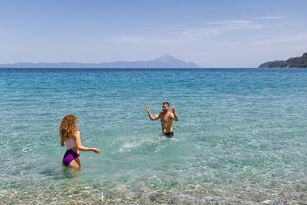Cheerful couple having fun while splashing each other at sea